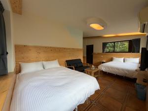 a bedroom with two beds and a chair in a room at 木木杉民宿 in Puli