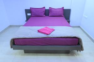 a large bed with purple sheets and purple pillows at Hotel Jaganmatha Kollur in Kollūru +2 photos