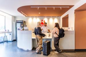 three people standing at a counter in a store at MEININGER Hotel Berlin Mitte in Berlin