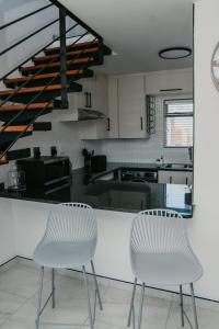 two white chairs sitting next to a kitchen at Gonubie Beachside Delight Apartment in East London