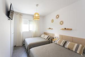 a bedroom with two beds and a tv and a window at AT Ponent VI in Oliva +6 photos
