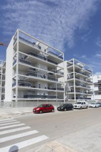 a large white building with cars parked in front of it at AT Ponent VI in Oliva