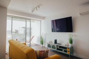 a living room with a couch and a tv on a wall at Atlantic Residence Pool & Ocean View in Câmara de Lobos