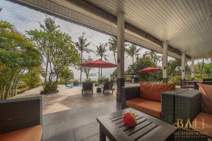 an outdoor patio with chairs and tables and umbrellas at Villa Burung, Bali - Breathtaking oceanfront, infinity pool in Tegallengah