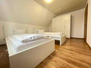 a white bedroom with a large bed and a cabinet at WEN112 gut geschnittene Monteurwohnung in Niederdorla +1 photo