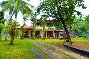 a house in the middle of a yard with trees at Niko Villa in Kosgoda