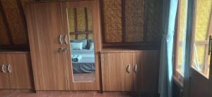 a wooden cabinet with a mirror in a bedroom at Five Time homestay Syariah in Selaparang