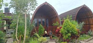 two people standing in front of a wooden house at Five Time homestay Syariah in Selaparang