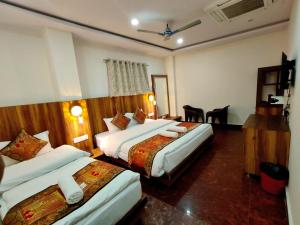 a hotel room with two beds and a table at Namaste Benares Varanasi in Varanasi