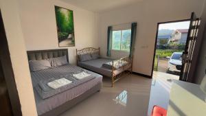 a bedroom with a bed and a couch and a window at Malee Guesthouse in Ban Rak Thai