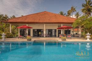 a villa with a swimming pool and red umbrellas at Villa Burung, Bali - Breathtaking oceanfront, infinity pool in Tegallengah