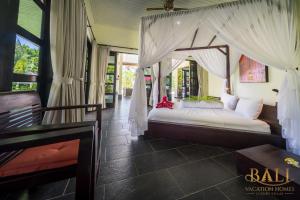 a bedroom with a bed with a canopy at Villa Burung, Bali - Breathtaking oceanfront, infinity pool in Tegallengah