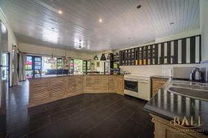 a large kitchen with wooden cabinets and a sink at Villa Burung, Bali - Breathtaking oceanfront, infinity pool in Tegallengah