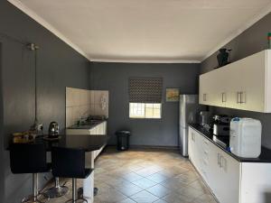 a kitchen with white cabinets and a black counter top at Kort a Moi in Lichtenburg