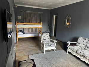 a bedroom with two bunk beds and two chairs at Kort a Moi in Lichtenburg
