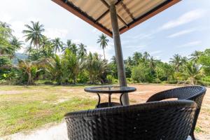 a table and chairs with a view of a field at Tonmai Suites III in Ko Lanta