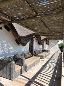 a patio with wicker couches under a wooden roof at Elands Bay Beach Villa in Elands Bay