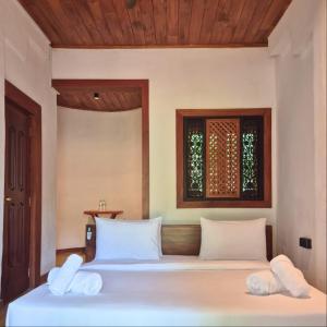 a bedroom with a bed with white sheets and a window at Tribe Wilpattu - Eco Lodge in Wilpattu
