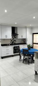 a kitchen with white cabinets and a blue table at Le Clus Stay in Bloemfontein