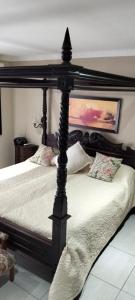 a bedroom with a black canopy bed with pillows at Le Clus Stay in Bloemfontein