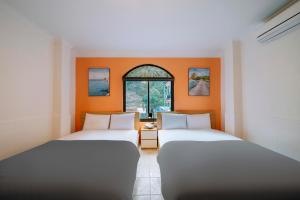 two beds in a room with an orange wall at Napoli Hostel Cat Ba in Cat Ba +151 photos