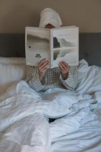a man laying in bed reading a book at Hotell City in Härnösand