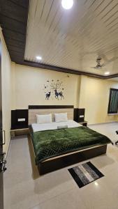 a bedroom with a large bed with a green blanket at Hotel Jai Palace in Pachmarhī