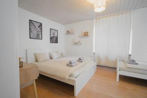 a white bedroom with a bed and a chair at Hostellerie des Princes-Evêques - Le Mystère in Porrentruy