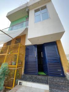 a house with blue doors and a fence at Giri Ashraya in Govardhan