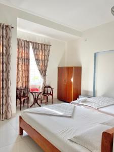 a bedroom with two beds and a table and a window at Nhà Minh Anh in Vung Tau