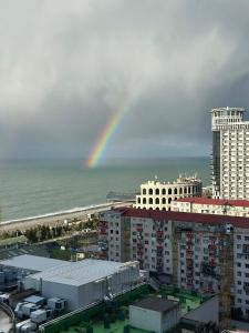 a rainbow over the ocean and a city with buildings at Solis Residence Batumi in Batumi
