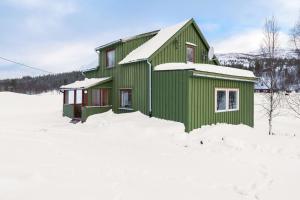a green house in the snow with snow at Nordnorge Self-Check-In in Majavatn