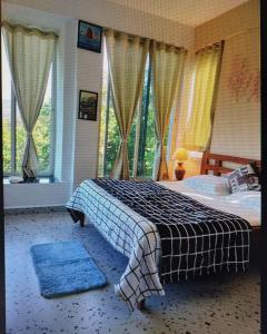 a bedroom with a bed with blue rugs and windows at Devrai Villa in Dapoli