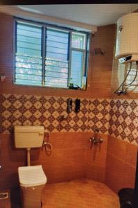 a bathroom with a toilet and a window at Devrai Villa in Dapoli