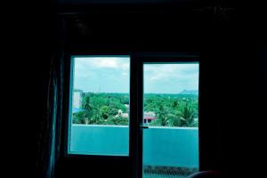 an open window with a view of a city at Hotel Rieejh in Nāgercoil