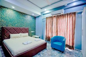 a bedroom with a bed and a blue chair at Hotel Rieejh in Nāgercoil +64 photos