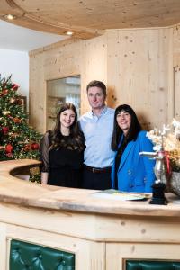 a man and two women standing in front of a counter at Garni Hotel Bel Vert in Selva di Val Gardena