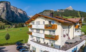 a hotel in the mountains with cars parked in front at Garni Hotel Bel Vert in Selva di Val Gardena