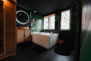 a bathroom with a white tub and a sink at Jungle Room Dunkerque centre in Dunkerque