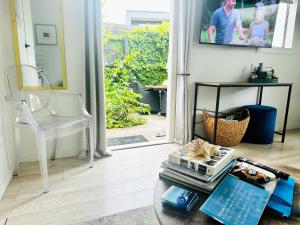 a living room with a glass coffee table and a sliding glass door at Private Beachside Studio with Courtyard and Sea view in Paraparaumu