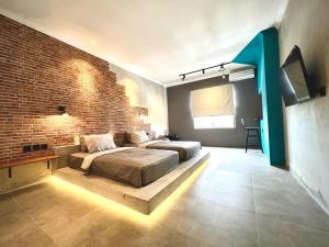 a bedroom with two beds and a brick wall at d'primahotel Yogyakarta in Yogyakarta