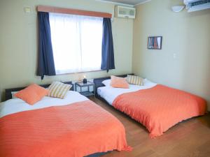 two beds in a room with a window at 9Stay函館 in Hakodate