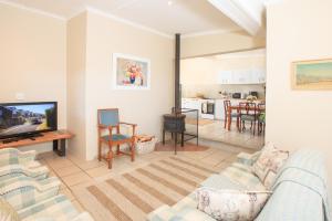 a living room with a couch and a tv at JoyWood Cottages in Himeville