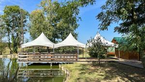 a pavilion with white tents in front of a pond at Savoy Village in Čokadinci