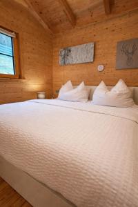 a bedroom with a white bed in a wooden room at Das Paradieschen Edlitz - stilvolles Blockhaus mit Kamin in Edlitz