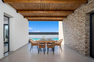 a dining room with a table and chairs and a brick wall at Villa Salty Sun 7 in Kremasti