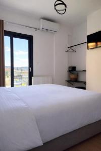 a white bedroom with a large bed and a window at White Rocks Meteora in Kalabaka +18 photos