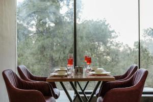 a table with chairs and wine glasses and a window at ELIVAAS Signature Pine view resort in Sabāthu