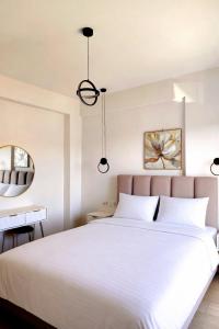 a bedroom with a white bed and a mirror at White Rocks Meteora in Kalabaka