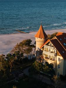 a large building with an orange roof next to the ocean at Zamek Łeba Resort & Spa in Łeba